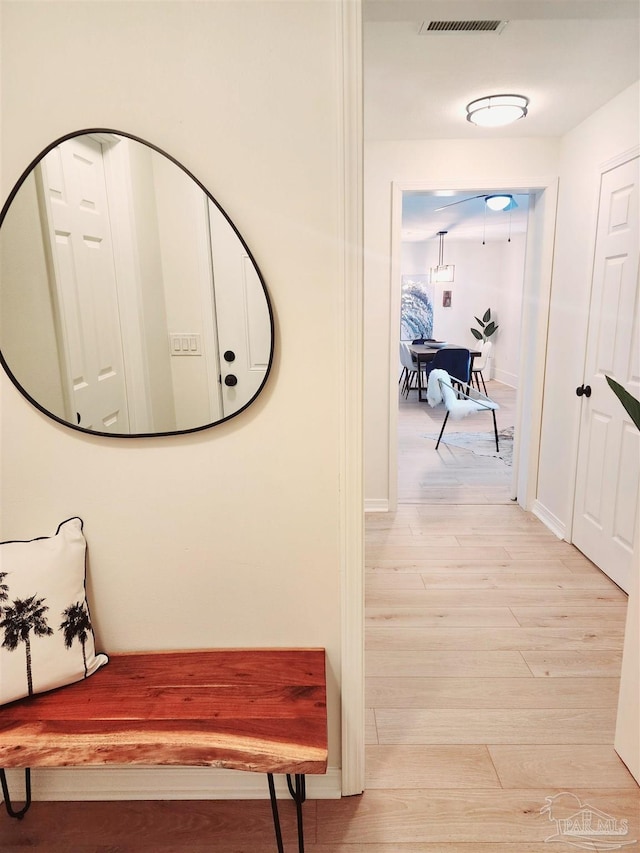 corridor featuring light wood-style floors, baseboards, and visible vents