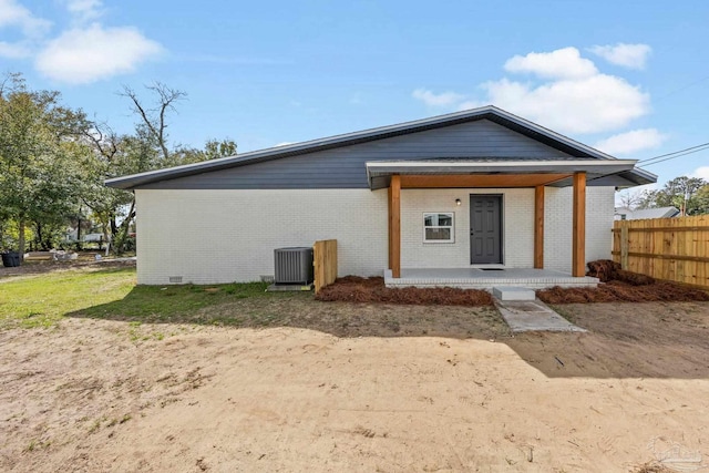 view of front of home featuring brick siding, a porch, crawl space, central AC, and fence