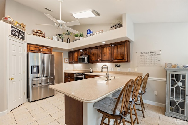9638 Wills Ln, Lillian, AL 36549 - kitchen featuring appliances with stainless steel finishes, light tile patterned floors, light countertops, a sink, and a breakfast bar area