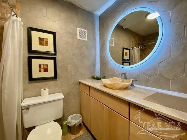 bathroom with tile walls, vanity, toilet, and visible vents