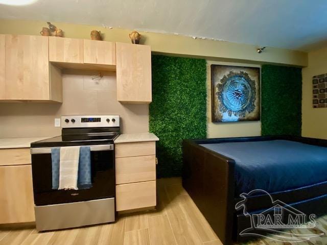 kitchen with light countertops, light wood-type flooring, and stainless steel range with electric cooktop