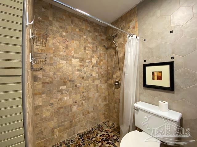 bathroom with tile walls, toilet, and a shower stall