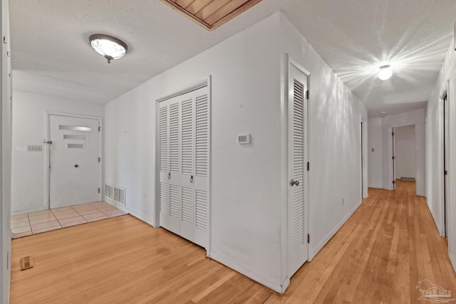 hallway featuring a textured ceiling and light hardwood / wood-style flooring