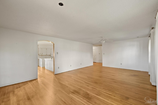 spare room featuring ceiling fan, light wood-type flooring, and a textured ceiling