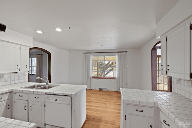 kitchen with tile counters, sink, backsplash, white dishwasher, and white cabinets