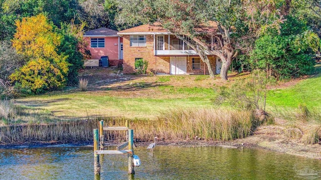 rear view of house featuring a lawn, a water view, and a balcony