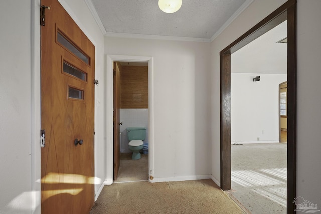 hall with light colored carpet, a textured ceiling, and ornamental molding