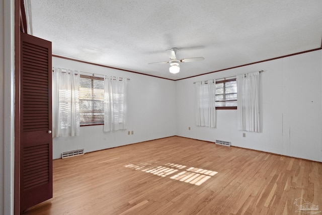 unfurnished room with a textured ceiling, a wealth of natural light, and light hardwood / wood-style flooring