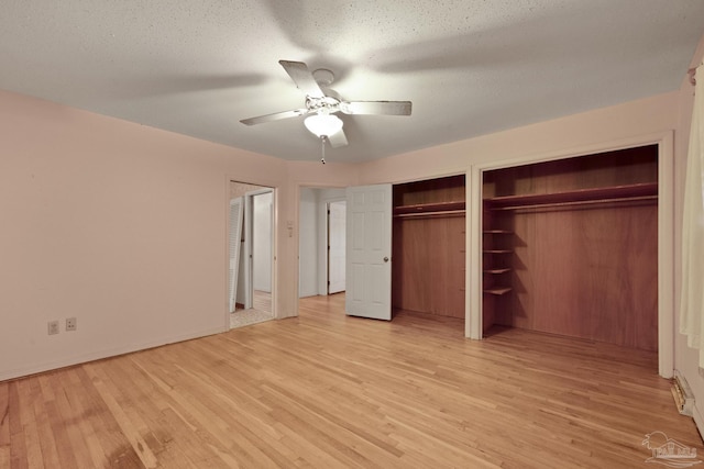 unfurnished bedroom featuring a textured ceiling, ceiling fan, light hardwood / wood-style flooring, and multiple closets