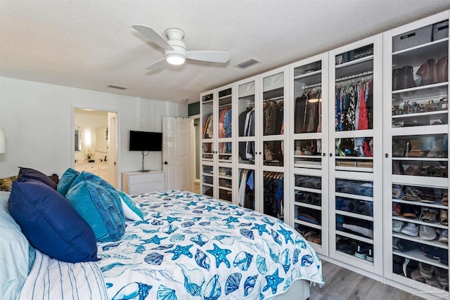 bedroom with hardwood / wood-style floors, a textured ceiling, ensuite bath, and ceiling fan