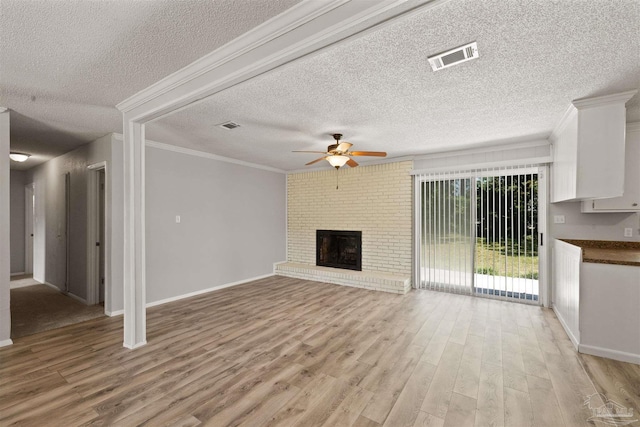 2500 Inda Ave, Pensacola, FL 32526 - unfurnished living room with visible vents, light wood-style flooring, ceiling fan, crown molding, and a brick fireplace