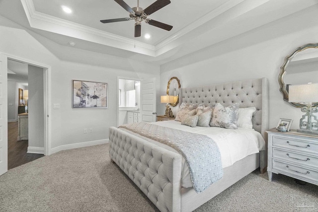 carpeted bedroom with ceiling fan, a raised ceiling, crown molding, and connected bathroom