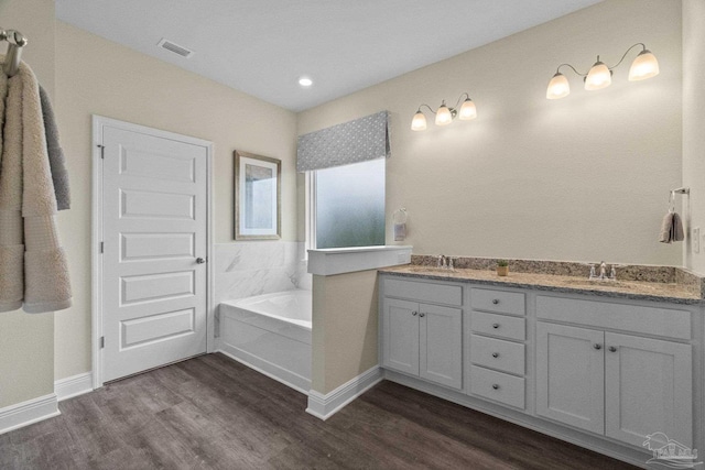 bathroom with vanity, a bath, and hardwood / wood-style flooring