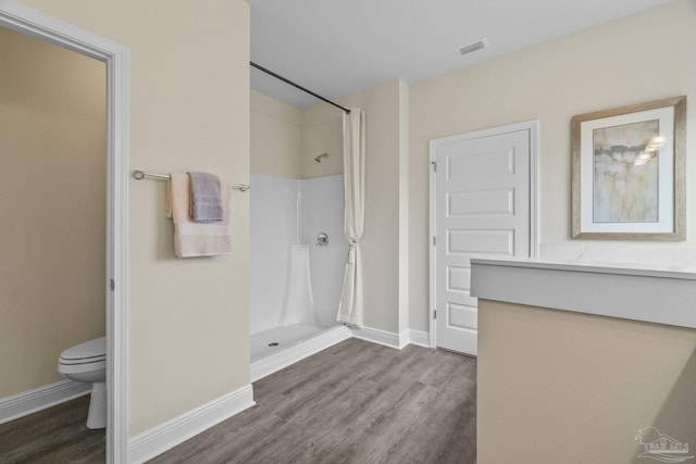 bathroom featuring hardwood / wood-style floors, toilet, and walk in shower