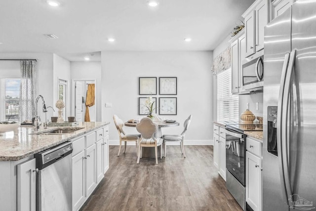 kitchen featuring sink, dark hardwood / wood-style floors, light stone countertops, white cabinetry, and stainless steel appliances