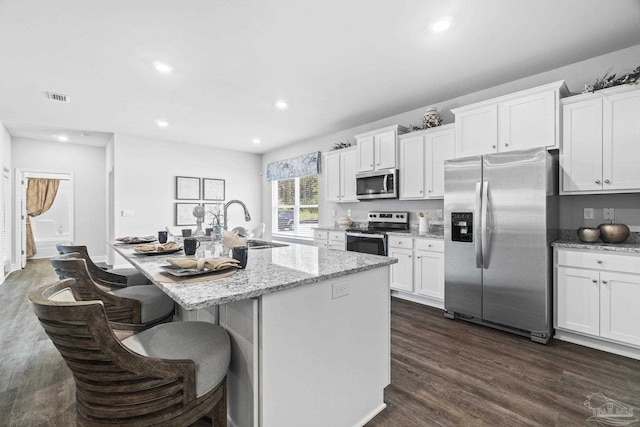 kitchen featuring dark hardwood / wood-style flooring, white cabinetry, stainless steel appliances, and an island with sink