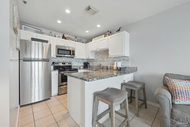 3191 Scenic Highway 98 Unit 212, Destin, FL 32541 - kitchen featuring stainless steel appliances, dark stone counters, white cabinetry, light tile patterned floors, and decorative backsplash
