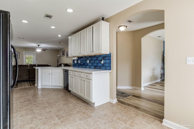 kitchen featuring white cabinetry, dishwasher, backsplash, kitchen peninsula, and black fridge