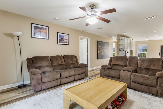 living room with sink, light hardwood / wood-style floors, and ceiling fan