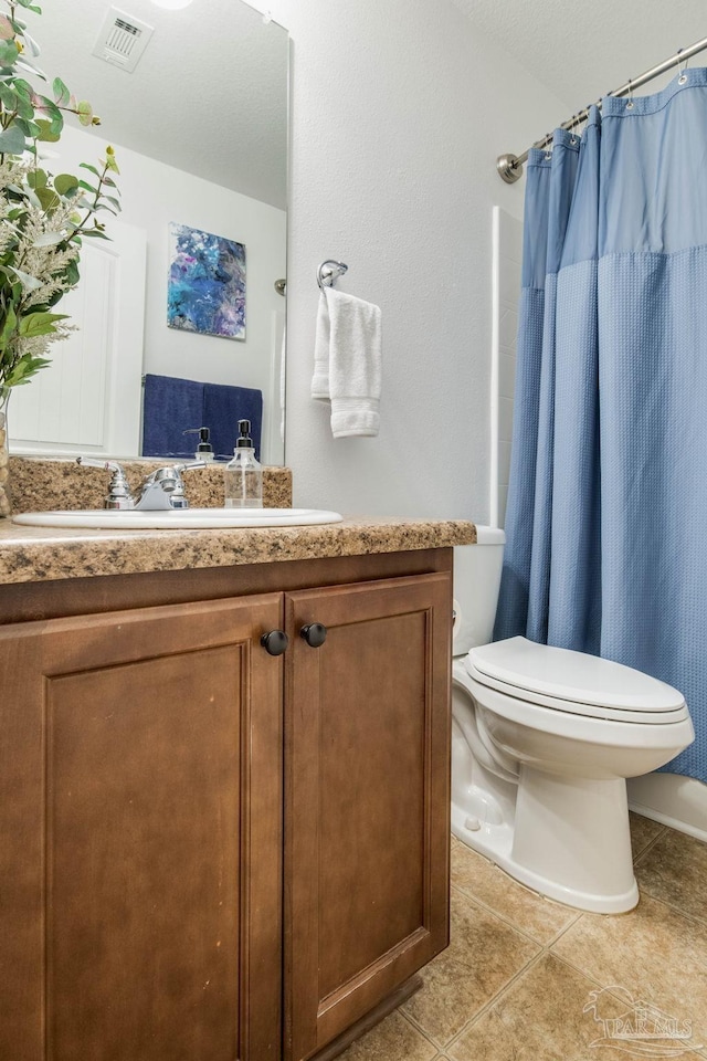 bathroom with a shower with curtain, vanity, toilet, and tile patterned flooring