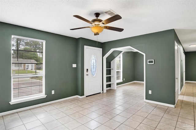 913 Bartow Ave, Pensacola, FL 32507 - foyer with a textured ceiling, ceiling fan, baseboards, light tile patterned flooring, and arched walkways