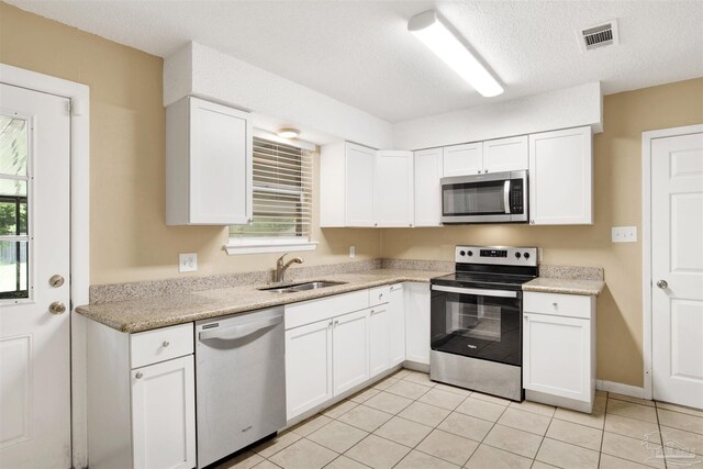 913 Bartow Ave, Pensacola, FL 32507 - kitchen with stainless steel appliances, a sink, white cabinets, and a textured ceiling