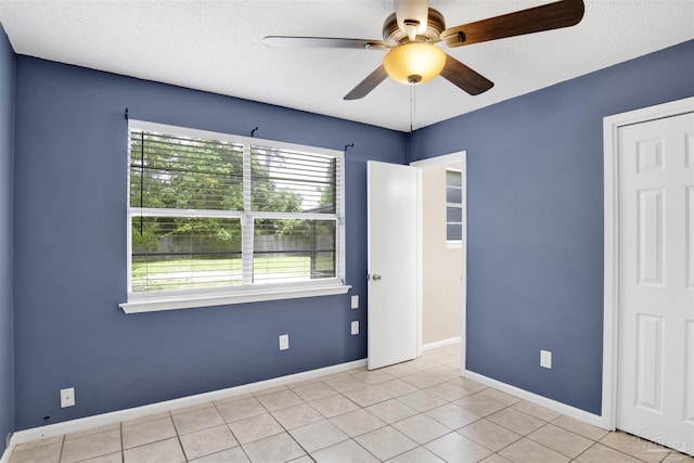 913 Bartow Ave, Pensacola, FL 32507 - empty room with a ceiling fan, a textured ceiling, light tile patterned floors, and baseboards