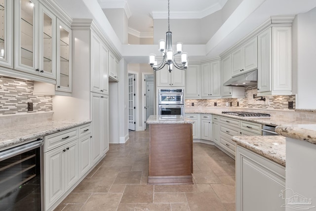 kitchen with light stone countertops, white cabinetry, stainless steel appliances, wine cooler, and hanging light fixtures