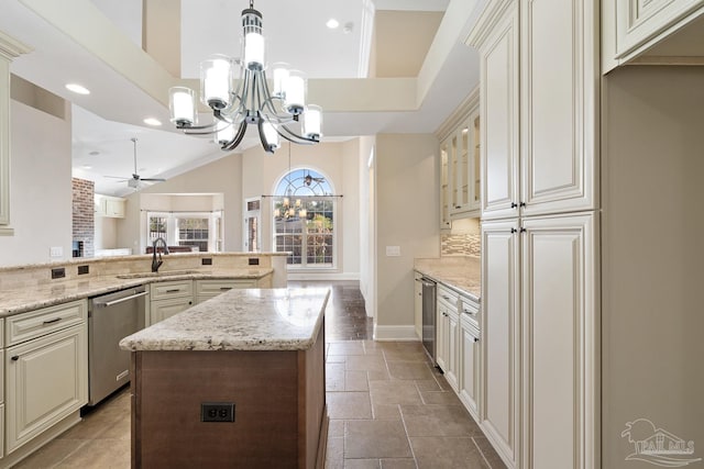 kitchen with light stone countertops, pendant lighting, dishwasher, sink, and cream cabinetry