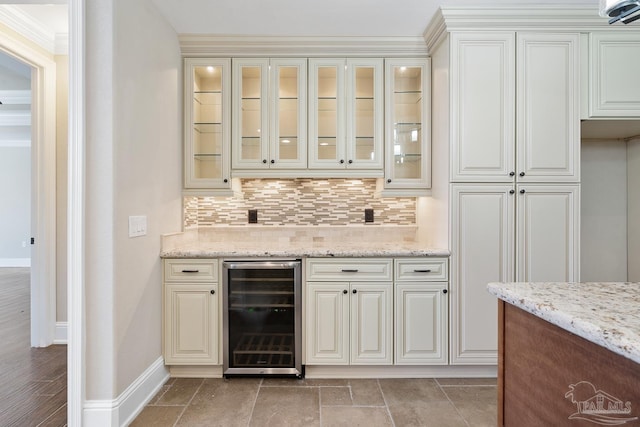 bar with wine cooler, tasteful backsplash, white cabinetry, ornamental molding, and light stone counters