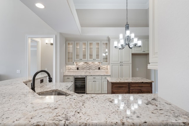 kitchen featuring light stone countertops, sink, beverage cooler, and pendant lighting