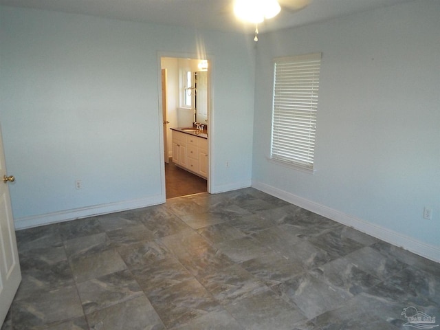 spare room featuring a sink, a ceiling fan, and baseboards