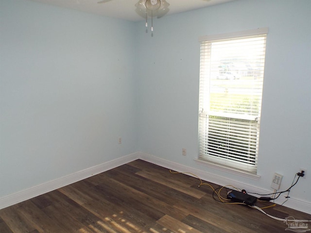 empty room featuring baseboards, dark wood-style floors, and ceiling fan