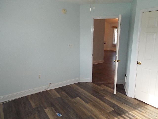 spare room with dark wood-style floors, baseboards, and a smoke detector