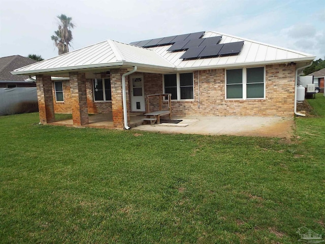 rear view of house with a standing seam roof, solar panels, a yard, a patio area, and metal roof