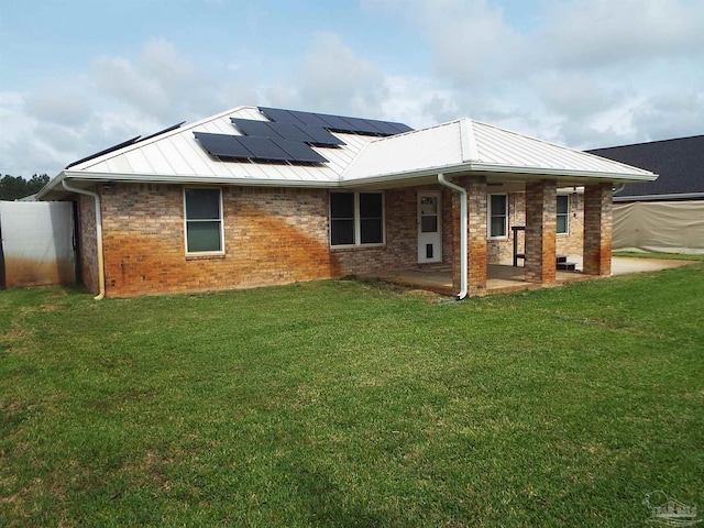 rear view of property with solar panels, a patio, metal roof, and a lawn