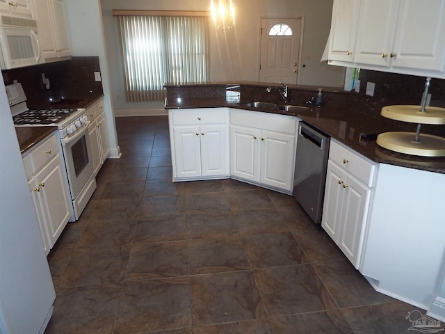 kitchen with white appliances, a peninsula, a sink, and dark countertops