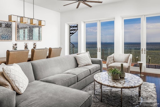 living room with dark wood-type flooring, ceiling fan, and a water view