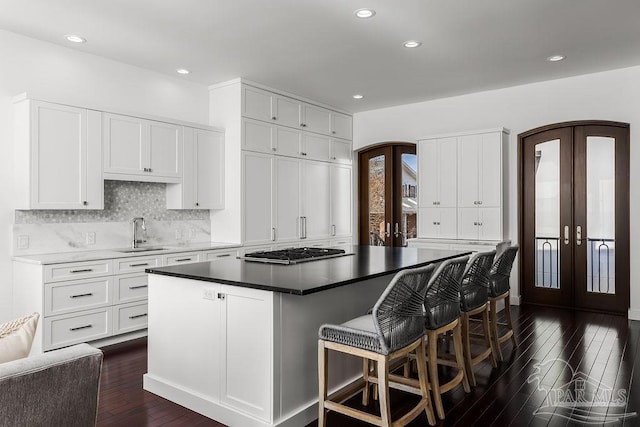 kitchen featuring a kitchen island, sink, white cabinets, stainless steel gas cooktop, and french doors