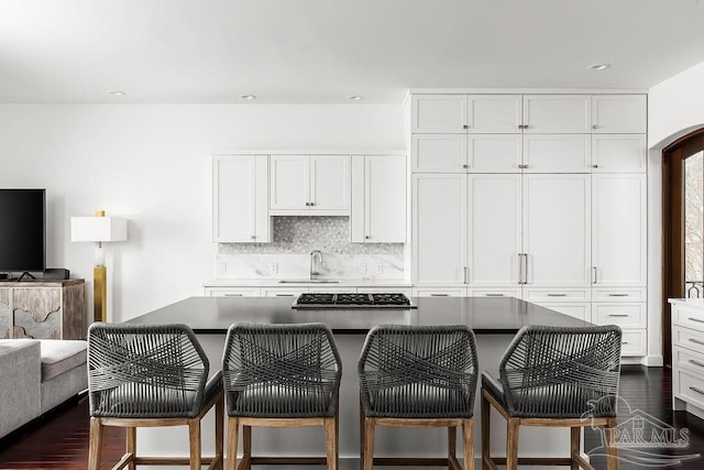 kitchen featuring white cabinetry, a center island, sink, and a kitchen breakfast bar