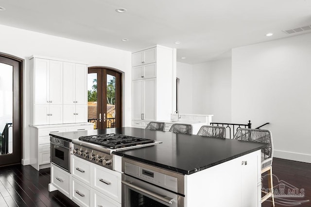 kitchen with appliances with stainless steel finishes, a breakfast bar, white cabinets, and french doors