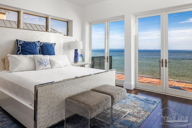 bedroom featuring dark hardwood / wood-style flooring, access to outside, and a water view