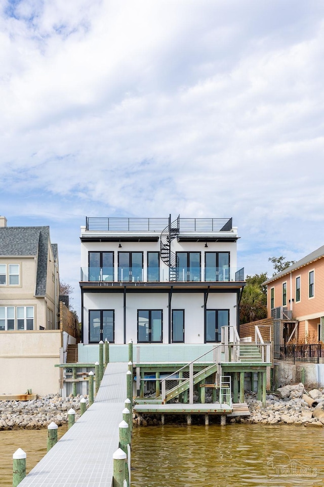 rear view of property featuring a balcony, a water view, and solar panels