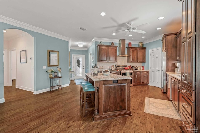 5757 Cobble Creek Dr, Pace, FL 32571 - kitchen featuring wall chimney range hood, arched walkways, a ceiling fan, light countertops, and recessed lighting