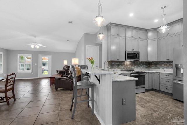 3774 Mcnemar Ct, Gulf Breeze, FL 32563 - kitchen with gray cabinetry, stainless steel appliances, a peninsula, open floor plan, and decorative backsplash