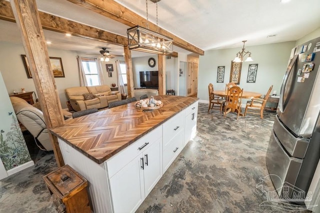 kitchen featuring white cabinetry, stainless steel fridge, ceiling fan, decorative light fixtures, and a kitchen island