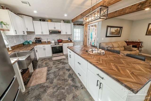 kitchen featuring visible vents, stainless steel appliances, butcher block counters, and white cabinetry