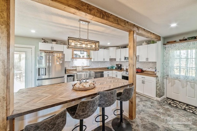 kitchen with white cabinets, butcher block countertops, and appliances with stainless steel finishes