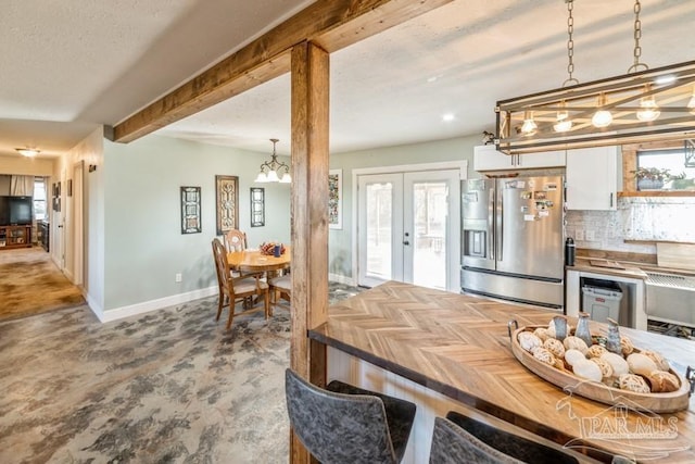 kitchen featuring white cabinetry, french doors, tasteful backsplash, hanging light fixtures, and stainless steel fridge