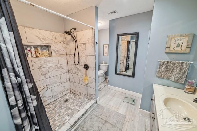 bathroom with toilet, vanity, visible vents, baseboards, and a stall shower